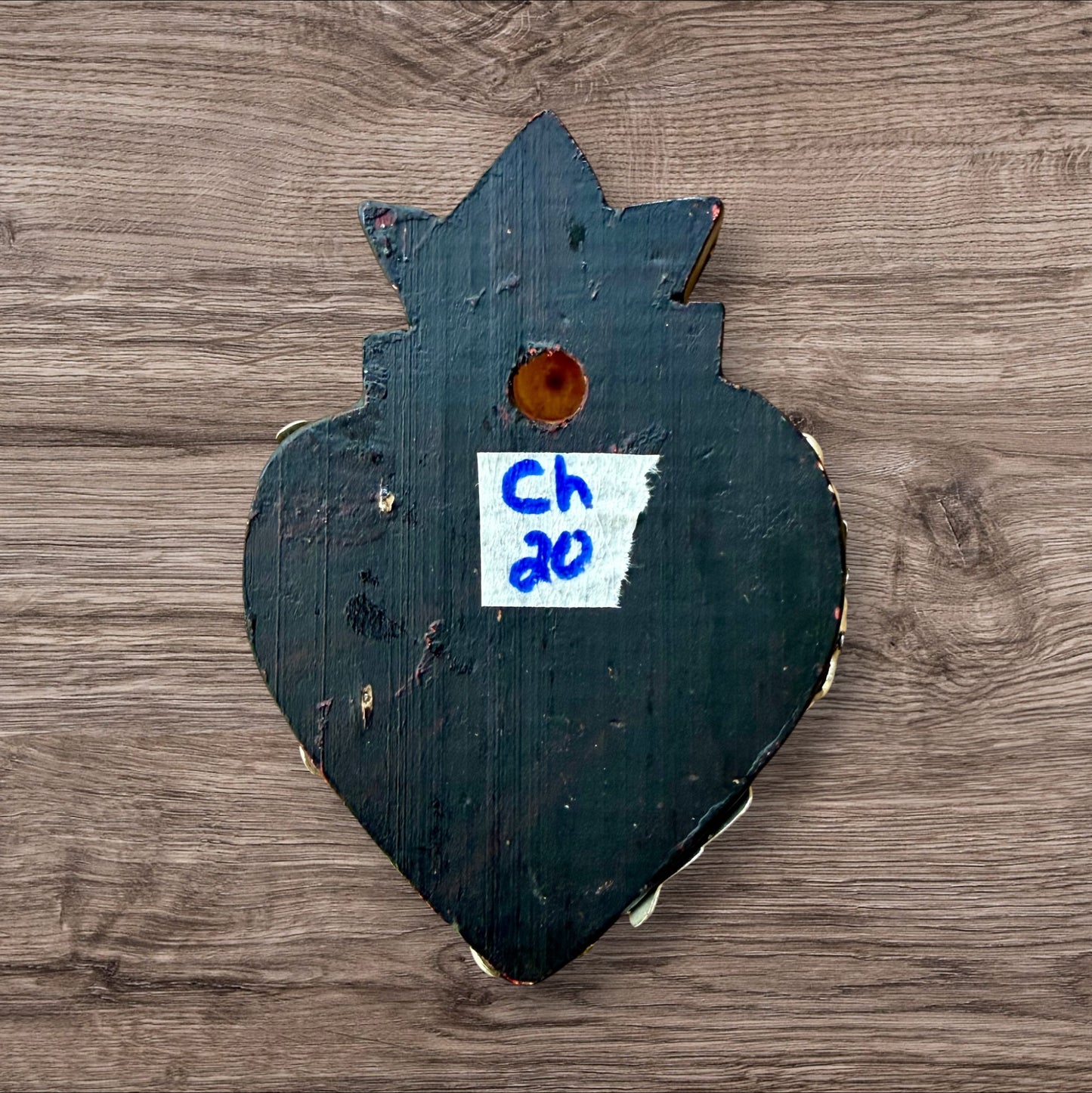 A Mexican Milagros heart in black with a gold flaming top, covered in antiqued charms.