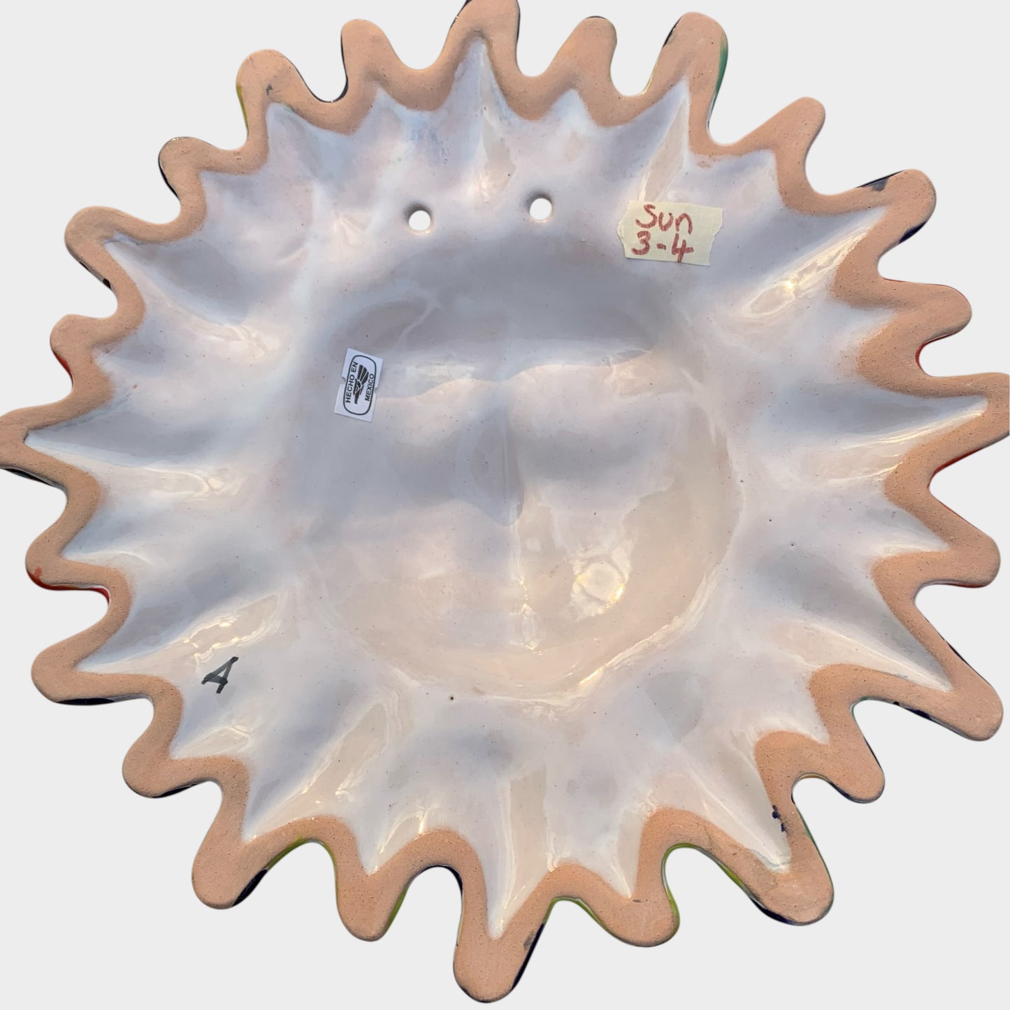 Decorative Talavera sun-shaped wall art with colorful face design on a white background Back view