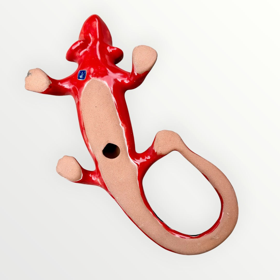 Mexican Talavera wall mounted iguana in bright red with multicolor designs bottom Showing opening to hang.