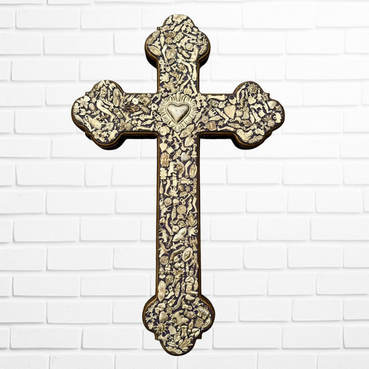 Decorative Milagros wood cross with many charms “miracles” on a white brick wall background