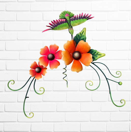 Decorative wall art with three orange flowers and hummingbird on a white brick wall background.