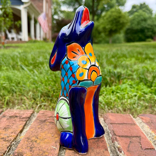 Coyote figurine on a brick surface with a garden background