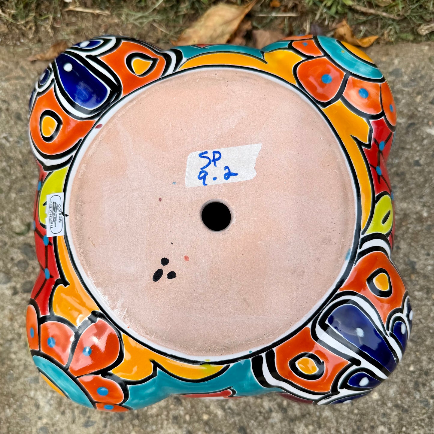 Hand painted Mexican Talavera Strawberry pot with a large top opening a four pockets on each side. Trim color is bright happy yellow, body has multi-color designs on each of the four sides. Photo of bottom drain hole.
