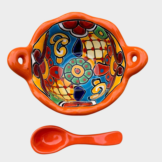 Colorful talavera salsa bowl with floral patterns and spoon on a white background