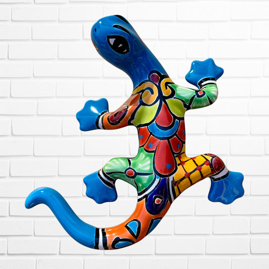 Colorful ceramic lizard wall art against a white brick wall background