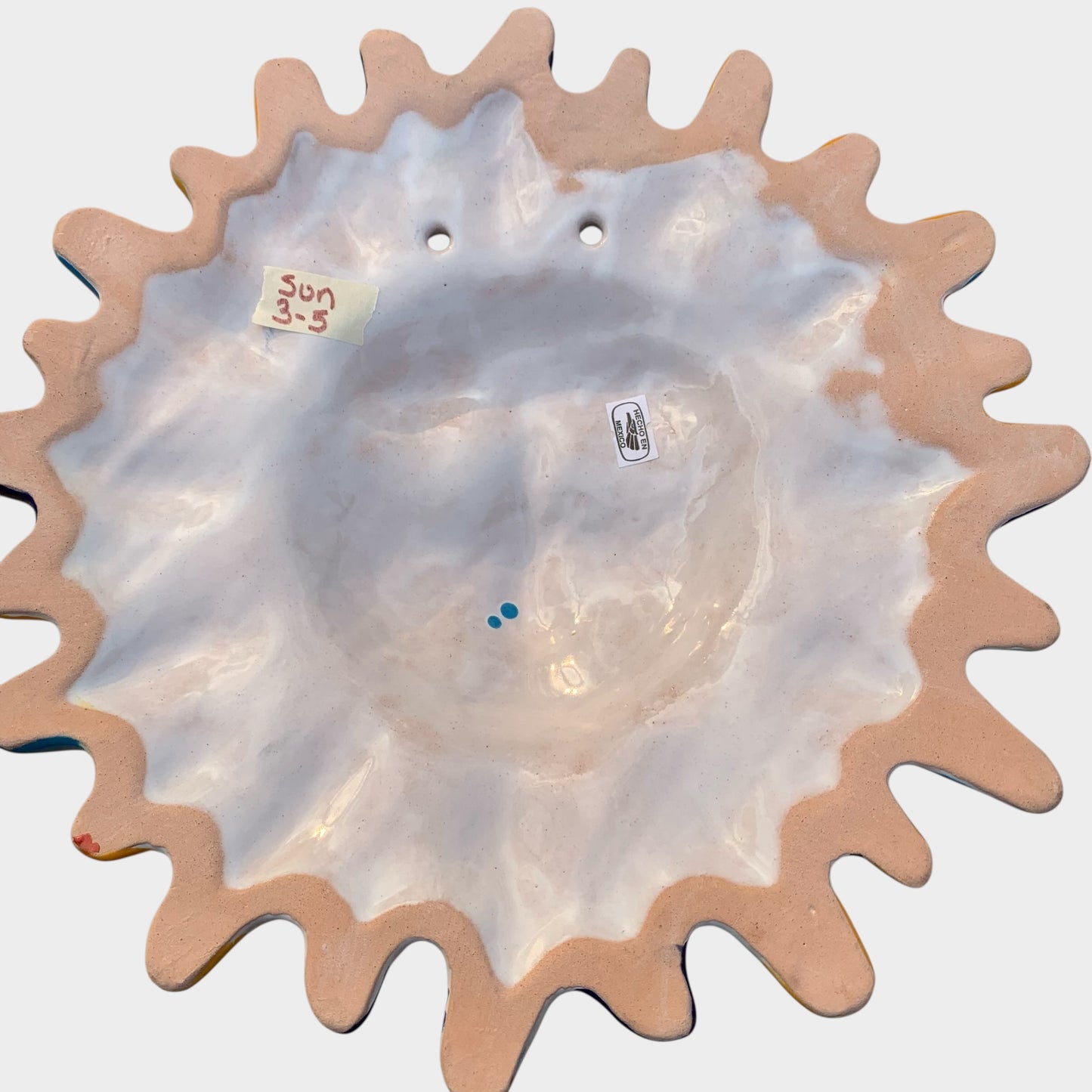 Decorative Talavera sun-shaped wall art with colorful face design on a white background Back view