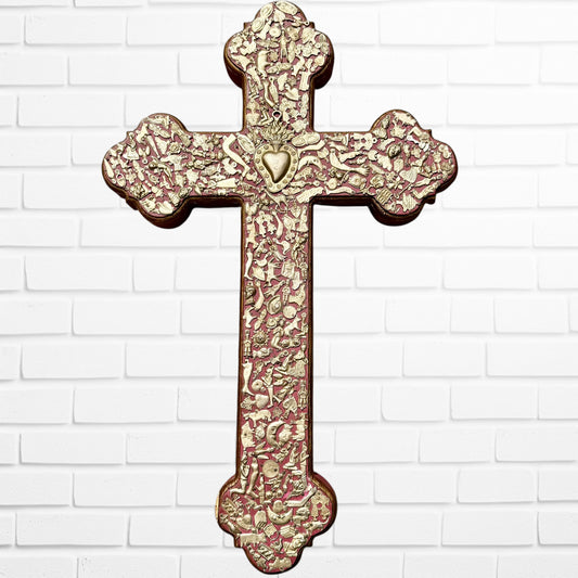 Decorative Milagros wood cross with many charms “miracles” on a white brick wall background