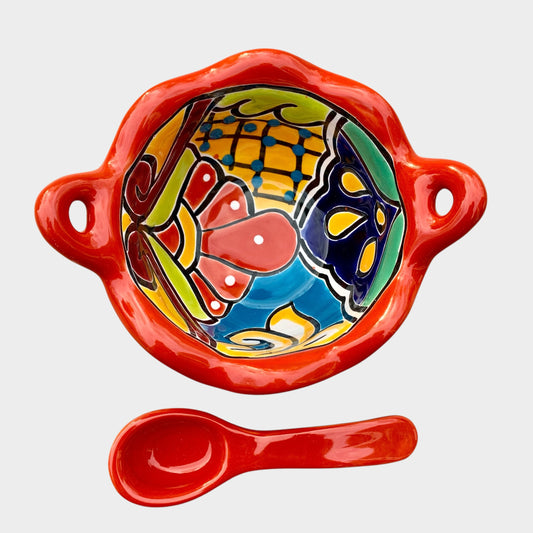 Colorful talavera salsa bowl with floral patterns and spoon on a white background