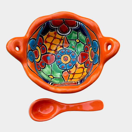 Colorful talavera salsa bowl with floral patterns and spoon on a white background