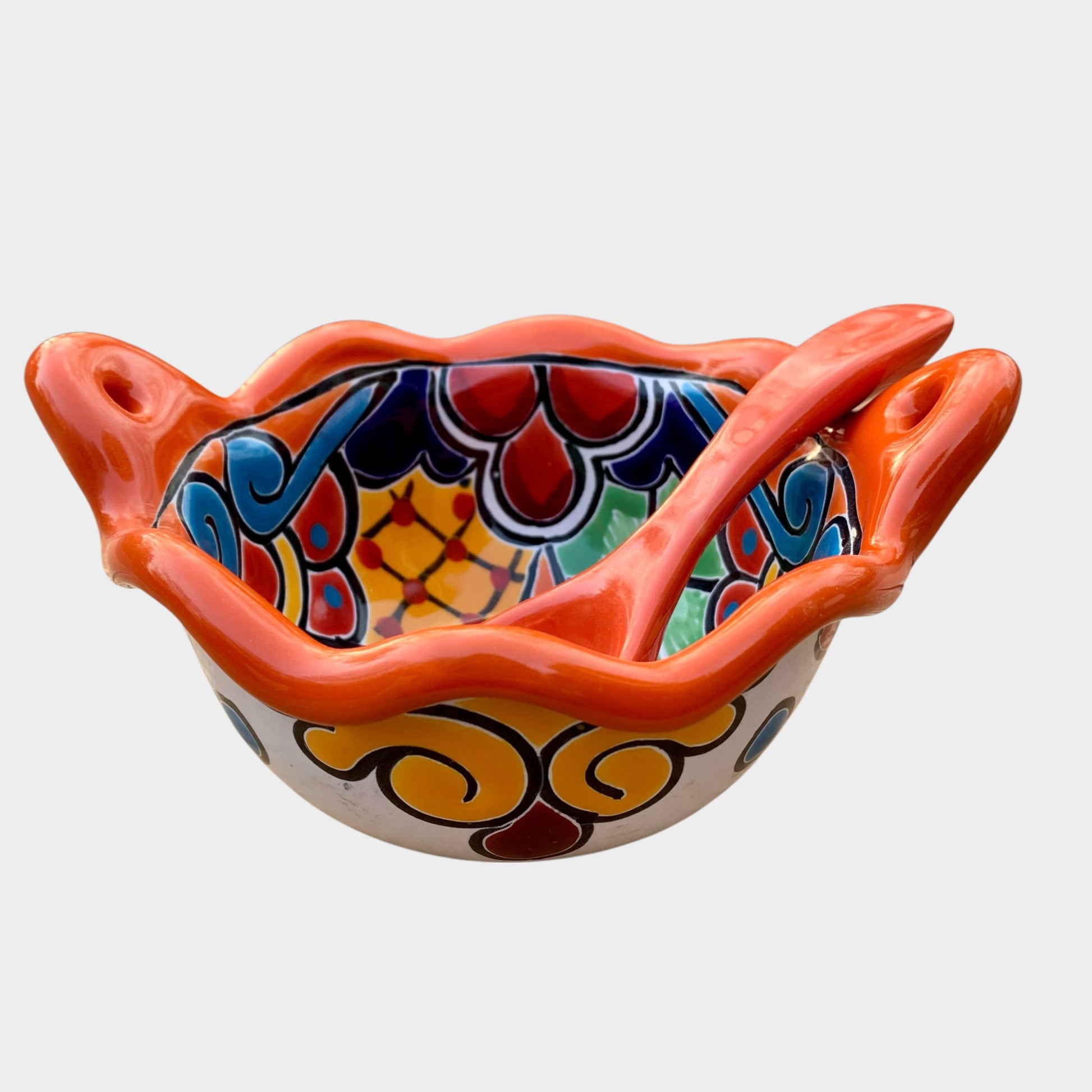 Colorful talavera salsa bowl with floral patterns and spoon on a white background Side view