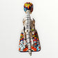 A ceramic Mexican-style skeleton dog figurine standing on a colorful floral base against a plain white background. Back view of catrina dog showing backbone.