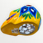A hand-painted ceramic sugar skull in vibrant yellow, decorated with colorful floral and geometric patterns in blue, purple, green, orange, and red, set against a plain white background bottom of skull.