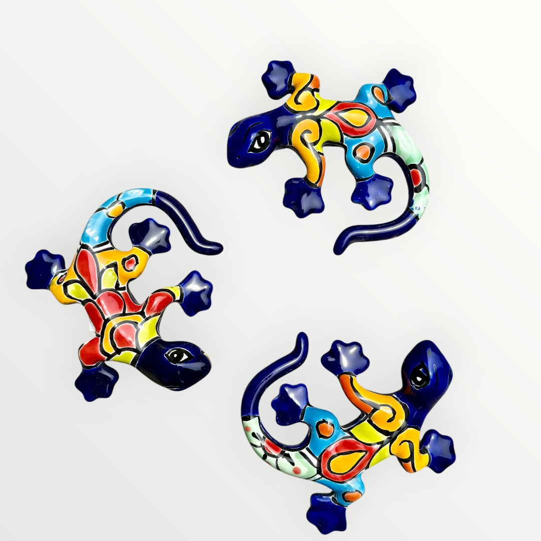 Three colorful Talavera ceramic lizards on a white background
