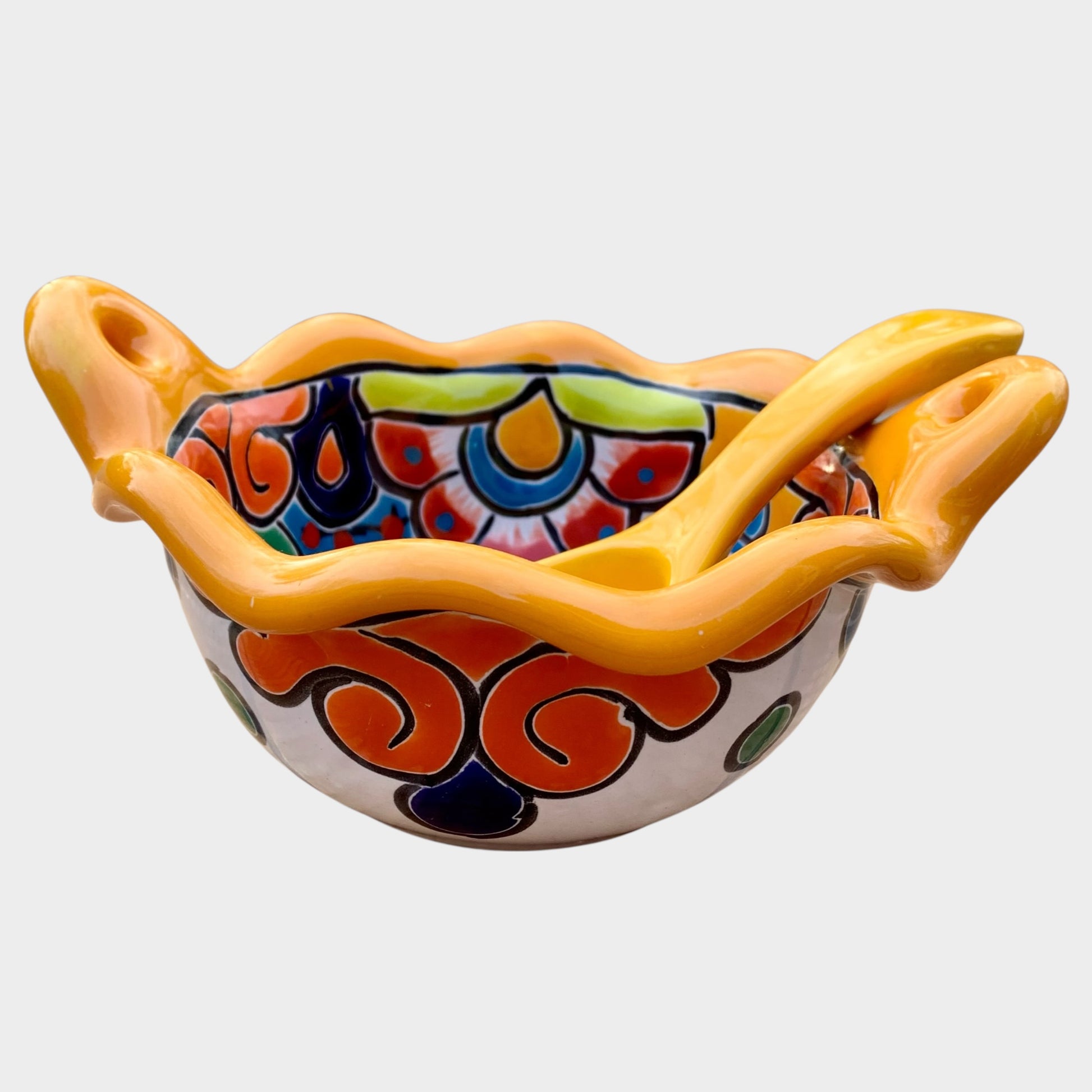 Colorful talavera salsa bowl with floral patterns and spoon on a white background Side view