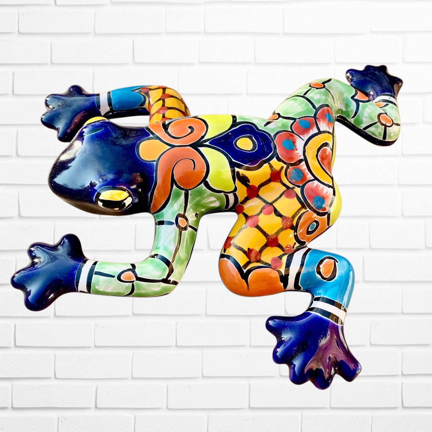 Colorful blue frog sculpture on a white brick wall right side