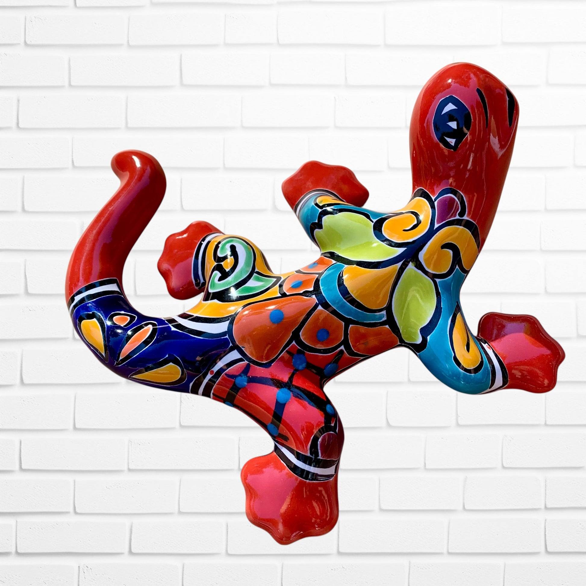 Colorful lizard-shaped sculpture against a white brick wall background left side