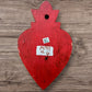 A Mexican Milagros medium heart in red with a gold and red flaming top, covered in antiqued golden charms, back view of heart.