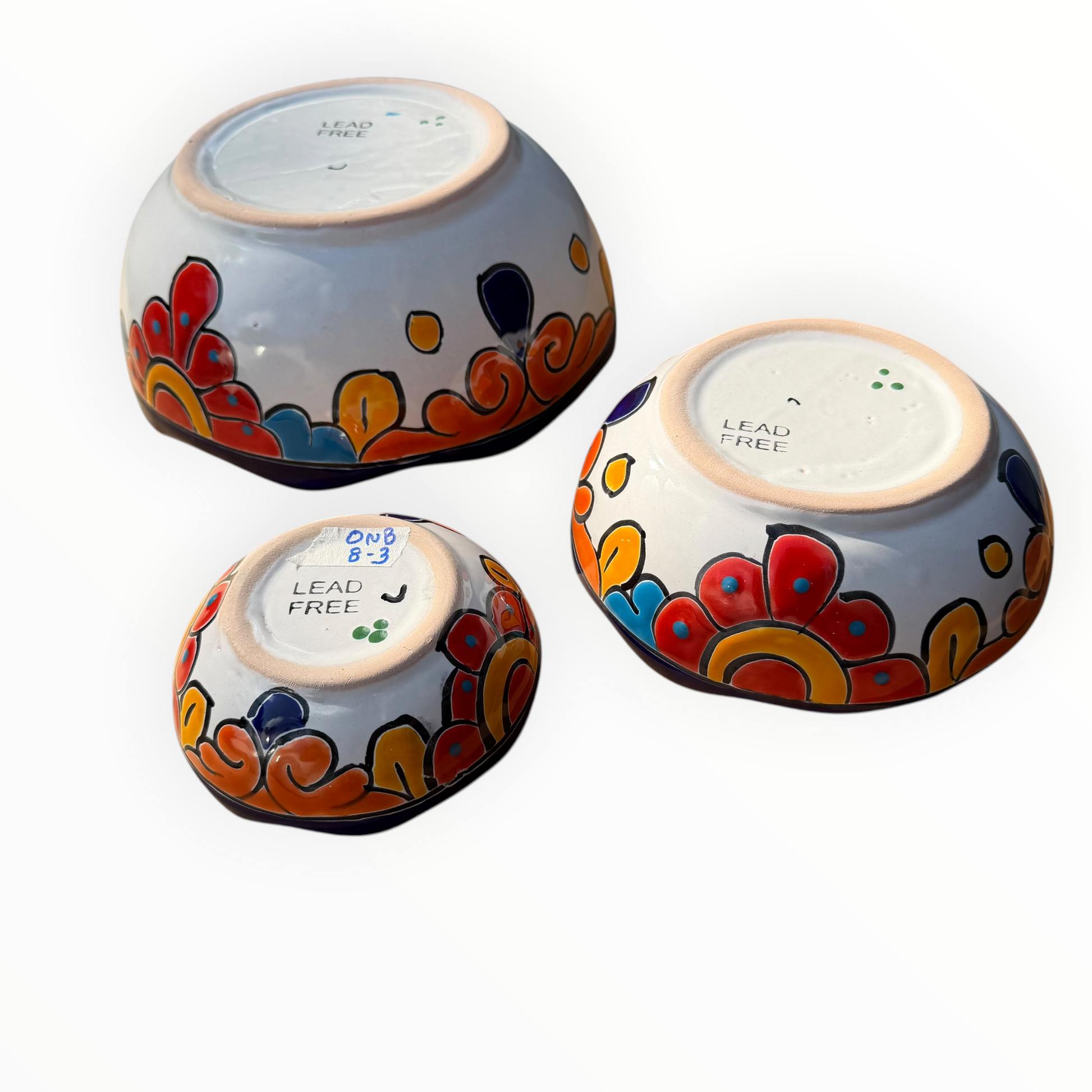 A set of nested, round Talavera ceramic bowls decorated with a vibrant, hand-painted Mexican Talavera style pattern featuring blue, yellow, orange, red, and green designs on a white background, bottom side view.