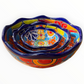 A set of nested, round Talavera ceramic bowls decorated with a vibrant, hand-painted Mexican Talavera style pattern featuring blue, yellow, orange, red, and green designs on a white background, side view of bowl.