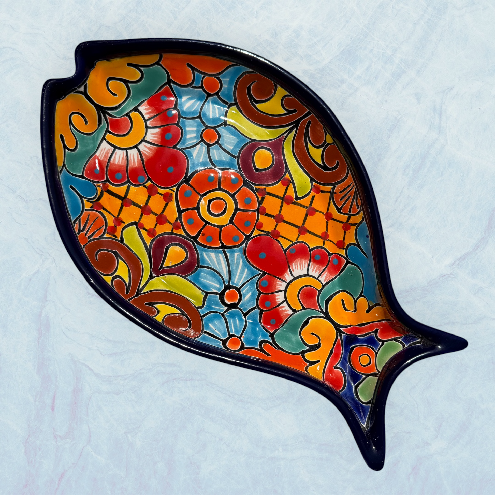 Blue decorative fish-shaped talavera serving plates with colorful hand-painted floral and geometric patterns, displayed on a light blue background.
