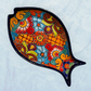 Blue decorative fish-shaped talavera serving plates with colorful hand-painted floral and geometric patterns, displayed on a light blue background.