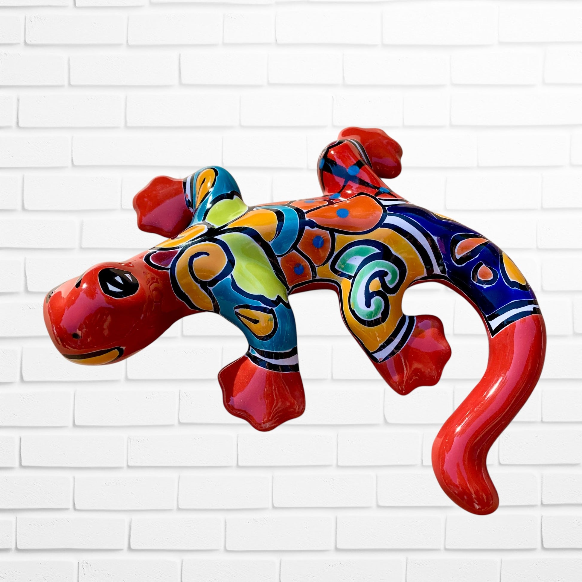 Colorful lizard-shaped inflatable toy against a white brick wall side view