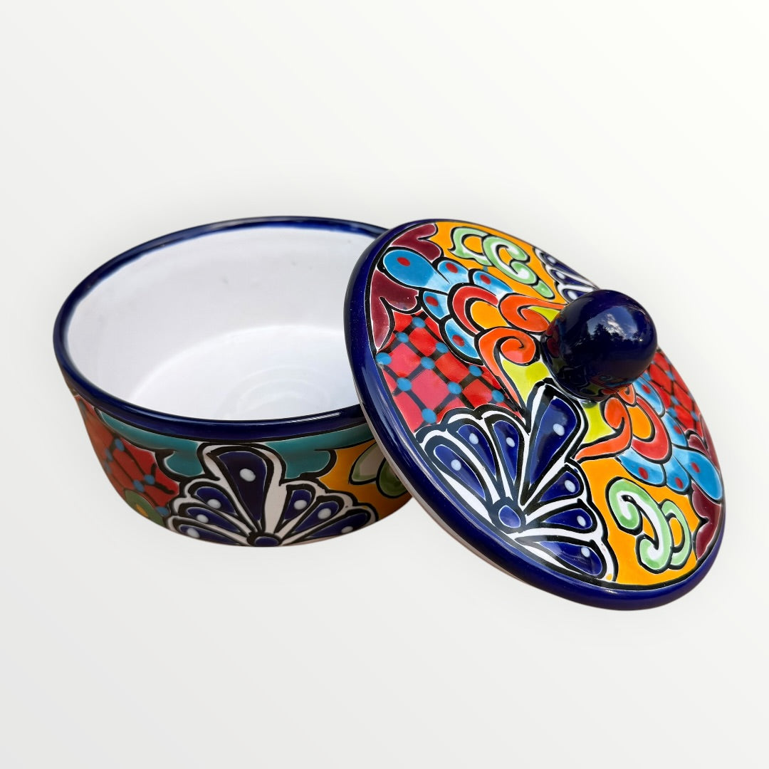 Mexican covered tortilla serving piece with blue rim and multi-color designs, slid is slightly off to show the interior of the bowl
