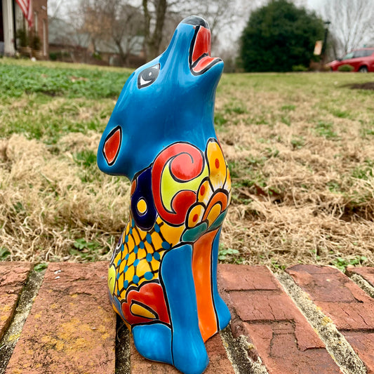 Colorful Talavera coyote sculpture on a brick surface with a grassy area in the background