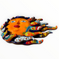 A colorful hand-painted Talavera ceramic sun wall sculpture with big wavy rays on a plain white background, view from the bottom.