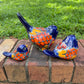 Three hand-painted ceramic bird figurines in different sizes, decorated with a vibrant Mexican Talavera style pattern of blue, red, yellow, and white, showing left side view
