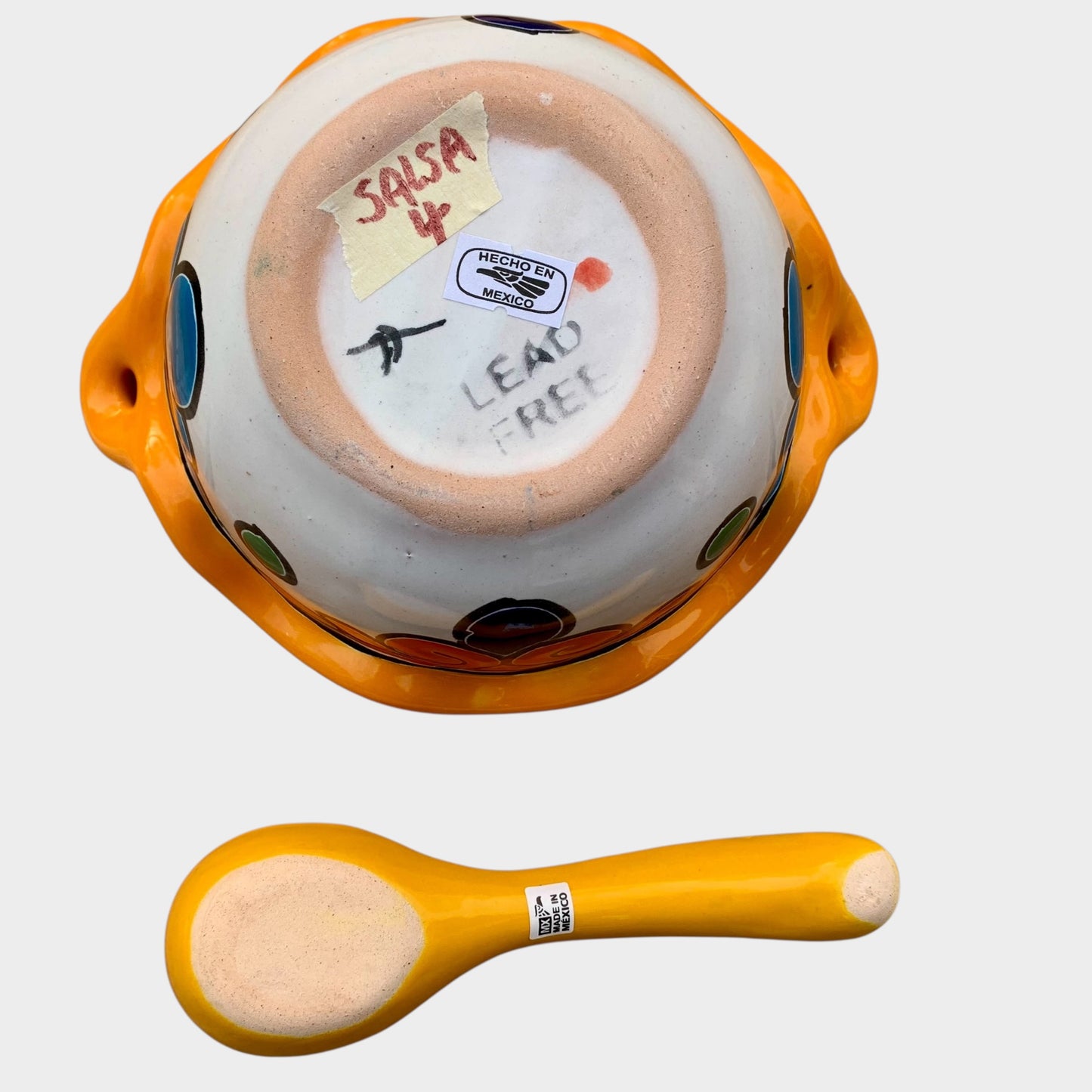 Colorful talavera salsa bowl with floral patterns and spoon on a white background Bottom view