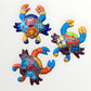 Three colorful hand-painted ceramic crabs arranged on a plain white background.