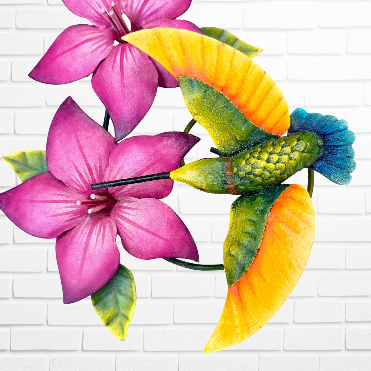 Decorative wall art with purple flowers and colorful hummingbirds on a white brick background bottom bird close up