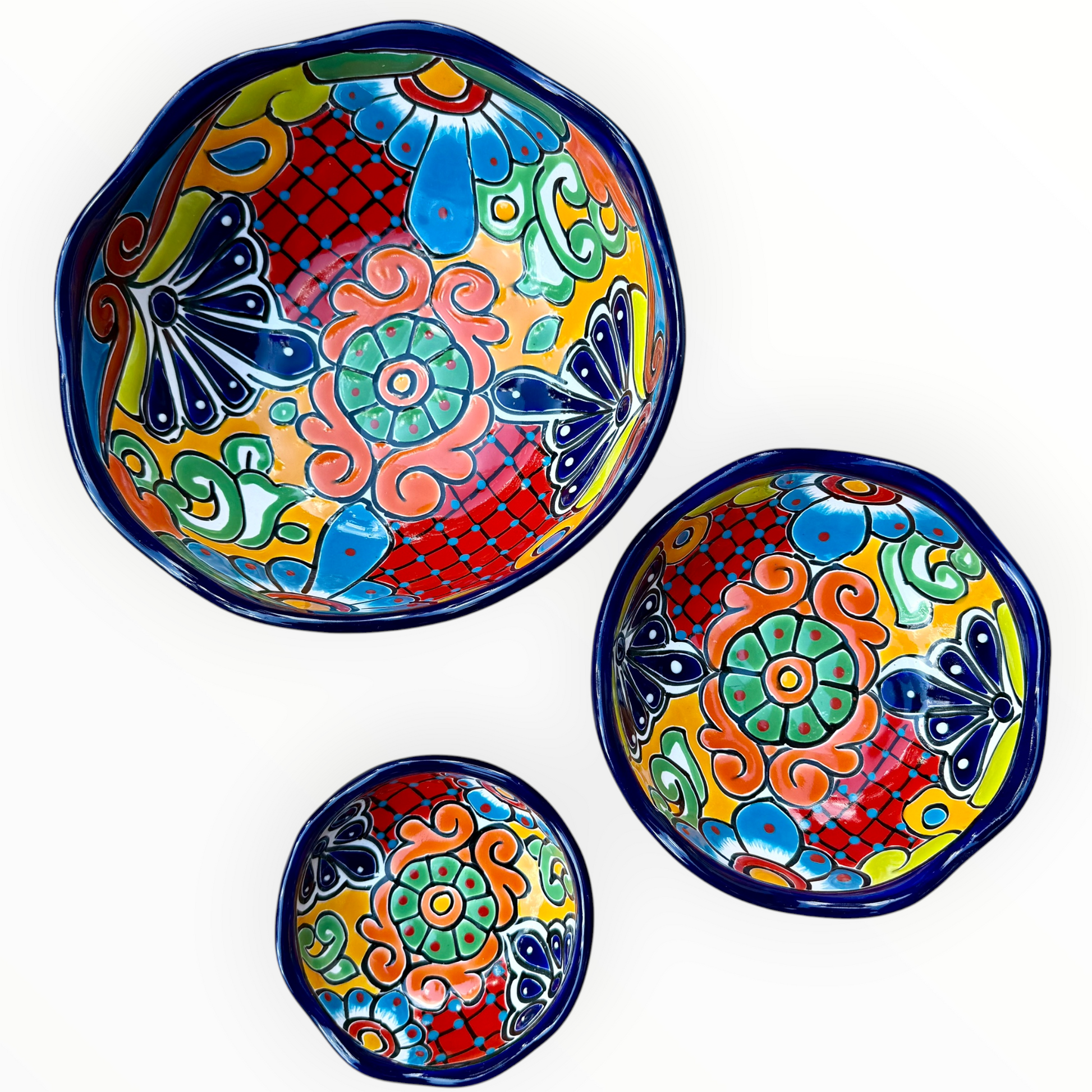 A set of three nested Talavera ceramic bowls with a vibrant hand-painted floral and geometric pattern in multiple colors, featuring a deep blue rim, shown on a plain white background, this photo shows all three bowls Separated.