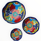 A set of three nested Talavera ceramic bowls with a vibrant hand-painted floral and geometric pattern in multiple colors, featuring a deep blue rim, shown on a plain white background, this photo shows all three bowls Separated.