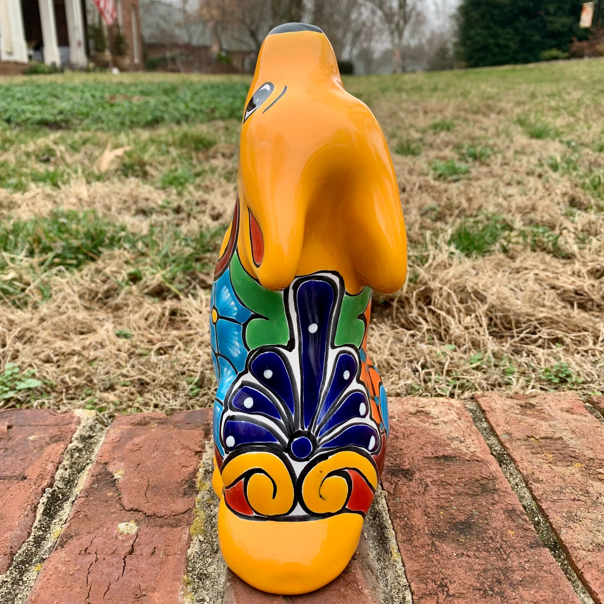 Decorative ceramic coyote with colorful patterns on a brick surface