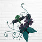 Decorative metal wall art with orange flowers and a hummingbird on a white brick background back
