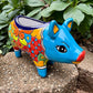 Colorful Talavera ceramic pig planter on a stone surface with green plants in  Background 