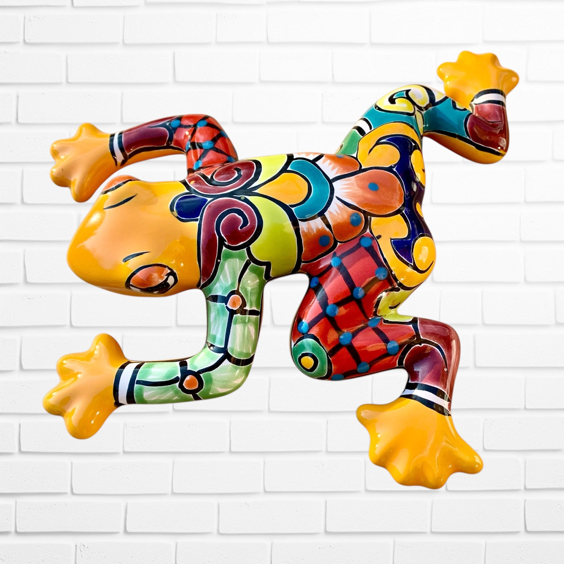 Colorful frog sculpture against a white brick wall background right sde 