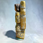 Milagros wooden guardian angel figurine wearing a yellow robe with gold and silver metallic details, standing on a light blue textured background, right side view.