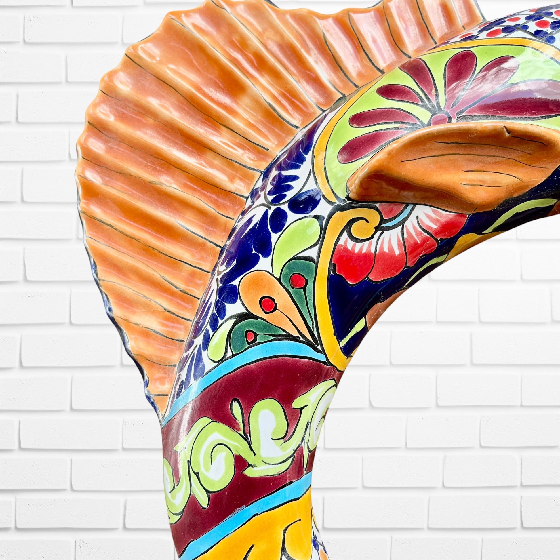 Colorful Mexican Talavera selfish sculpture against a white brick wall Body detail