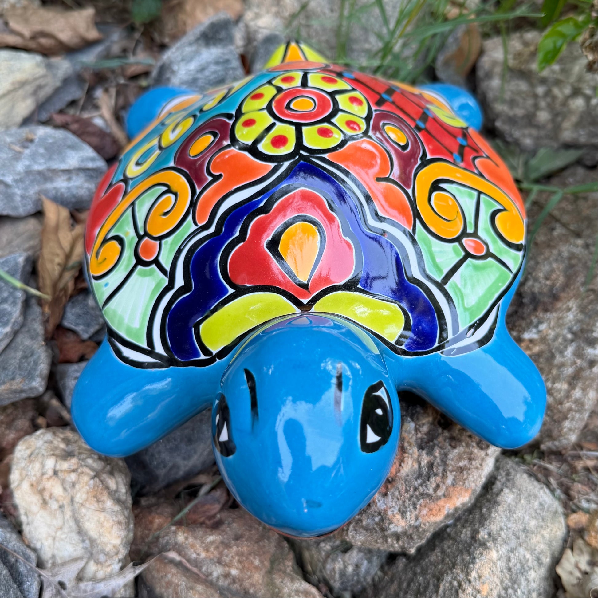 Colorful Mexican Talavera ceramic turtle figurine on a natural stone background Front