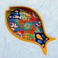Yellow fish-shaped Talavera  serving dishes with colorful hand-painted floral and geometric patterns, displayed on a light blue textured background.