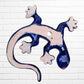A colorful Talavera ceramic wall sculpture of a salamander, featuring a glossy finish and intricate hand-painted patterns in blue, orange, red, yellow, and white, mounted against a white brick wall, fairview Showing hole for wall mounting.