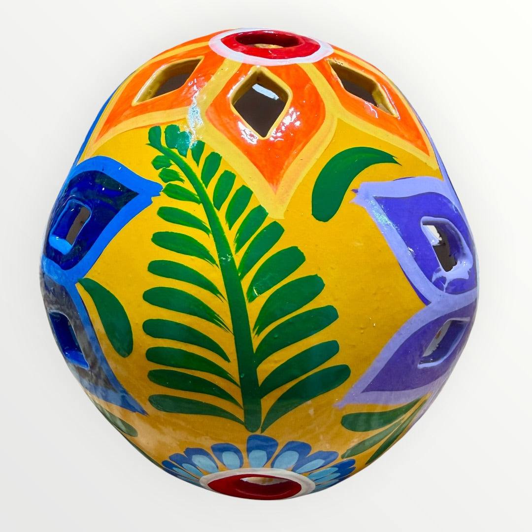 A hand-painted ceramic sugar skull in vibrant yellow, decorated with colorful floral and geometric patterns in blue, purple, green, orange, and red, set against a plain white background back skull view.