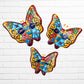 Three colorful talaver butterfly wall art pieces with a traditional style pattern, displayed against a white brick wall.