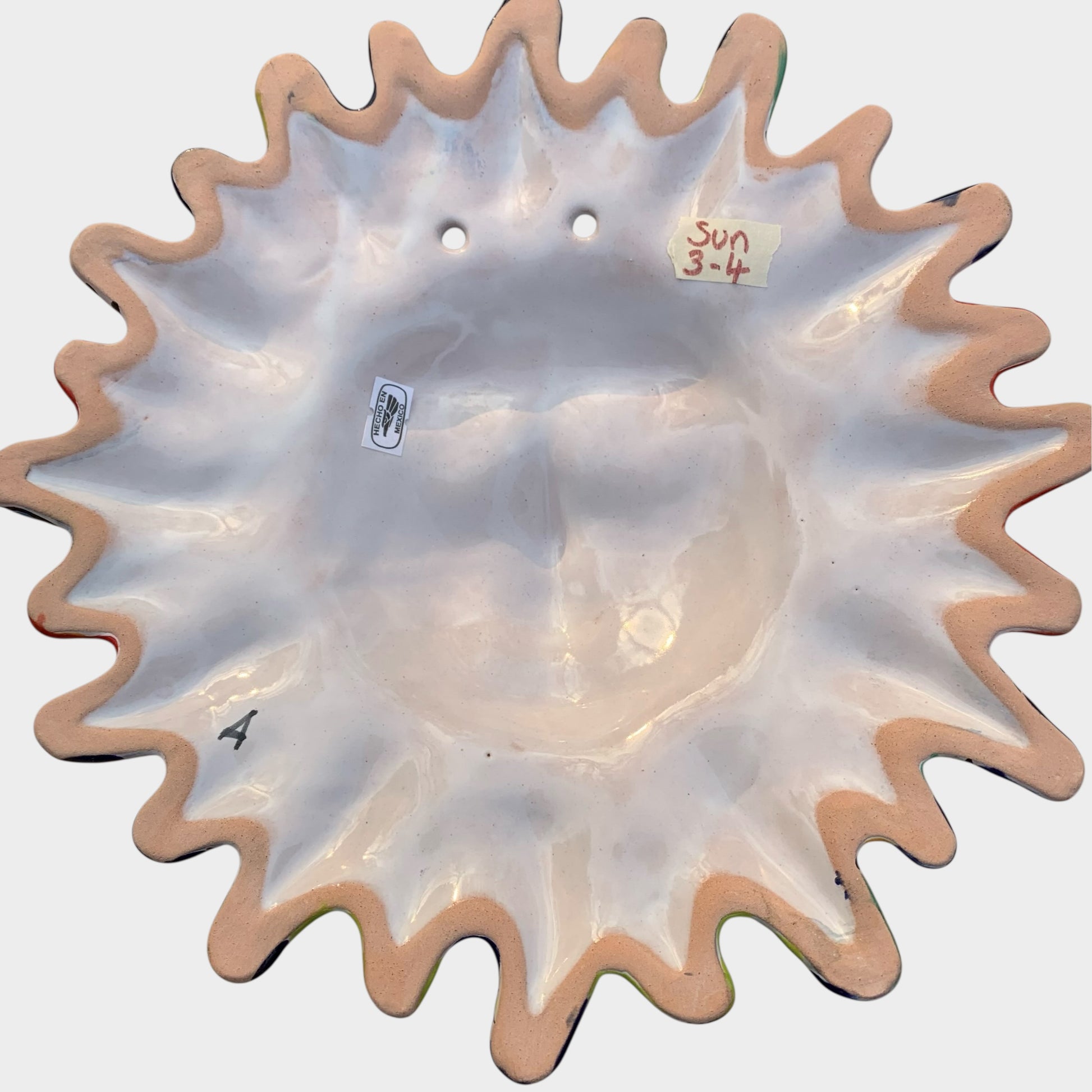 Decorative Talavera sun-shaped wall art with colorful face design on a white background Back view