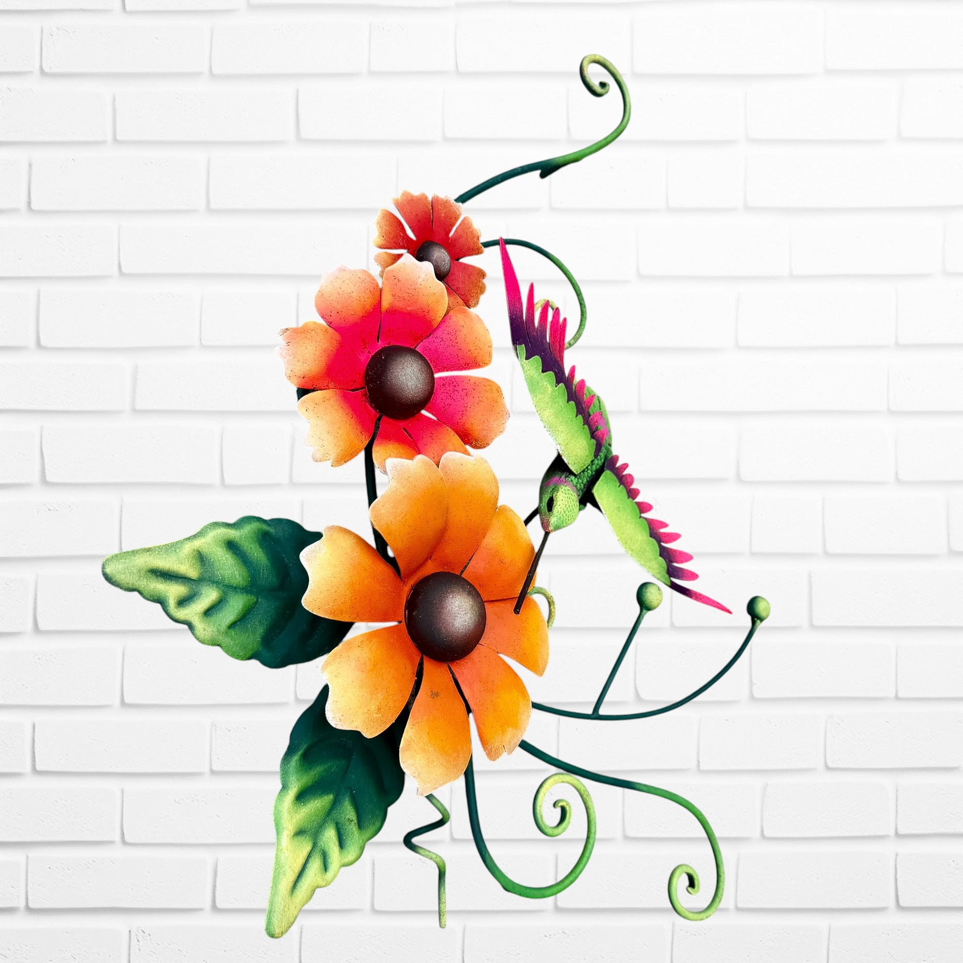 Decorative metal wall art with orange flowers and a hummingbird on a white brick background side view