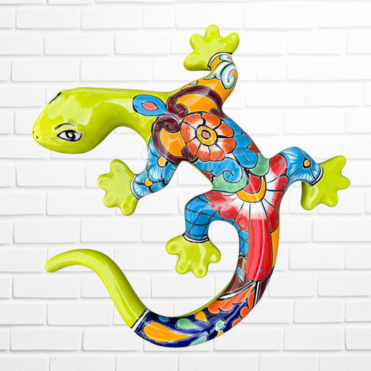 A colorful decorative lizard Talavera wall sculpture with a hand-painted floral and geometric pattern, mounted against a white brick wall.