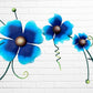 Decorative metal wall art with three blue flowers and a colorful hummingbird on a white brick background floral close up
